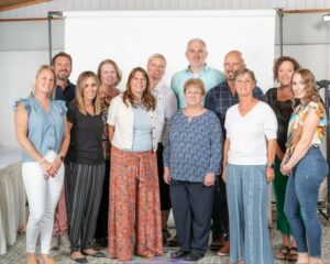 Meet Our Team - Ethos Agents Posing for a Group Photo In an Office in Front of a Projector Screen